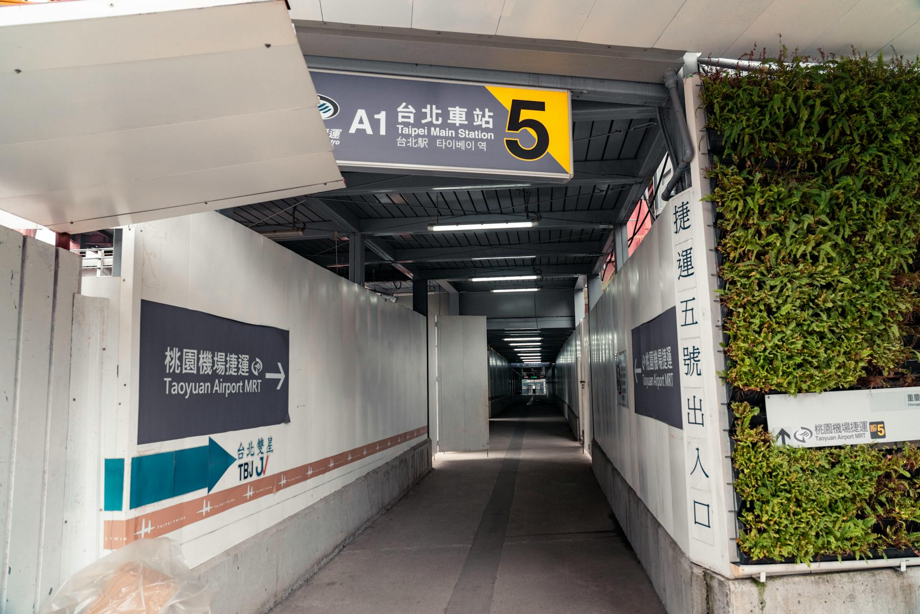 Covered walkway leading to Taipei Main Station Exit 5 with signs to Taoyuan Airport MRT.